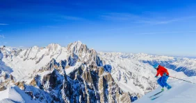 A skier heads down the mountain under blue skies